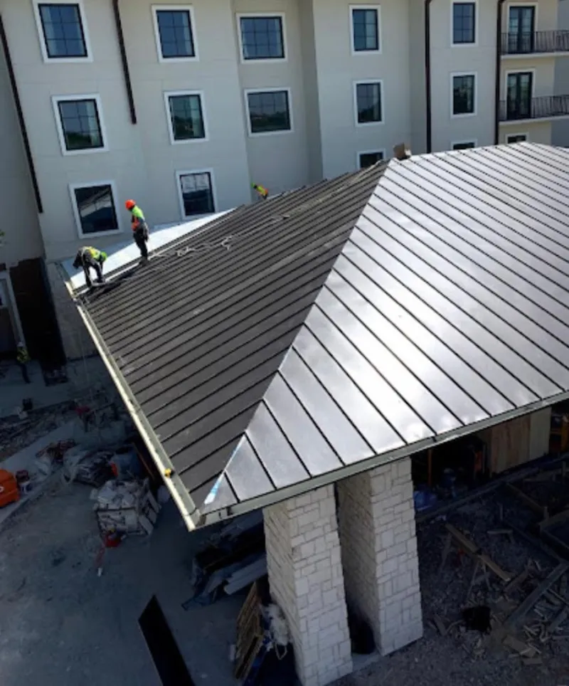 Crew installing standing seam metal roof panels on a commercial project in Oakdale
